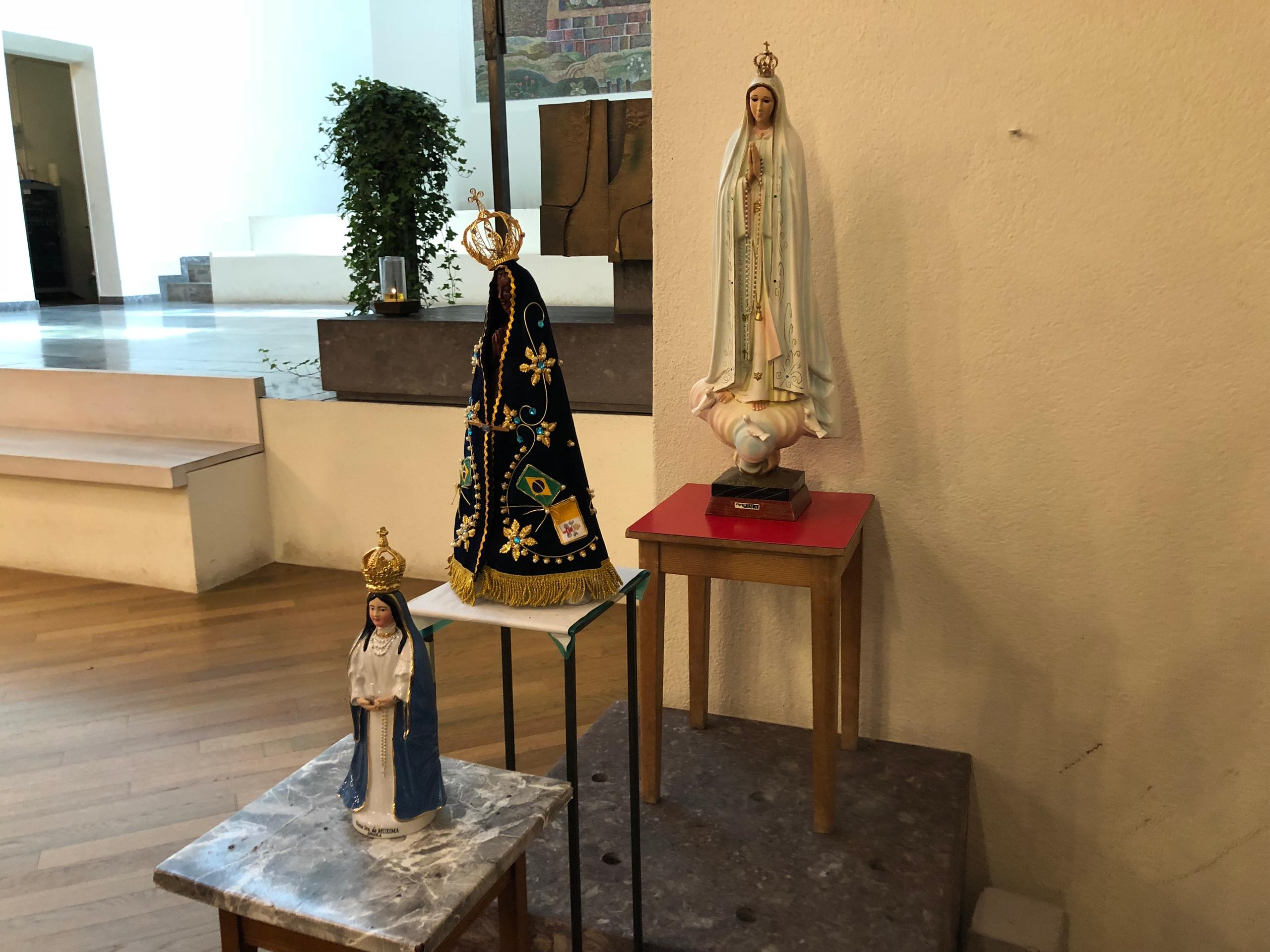 Três imagens religiosas próximas ao altar de uma igreja