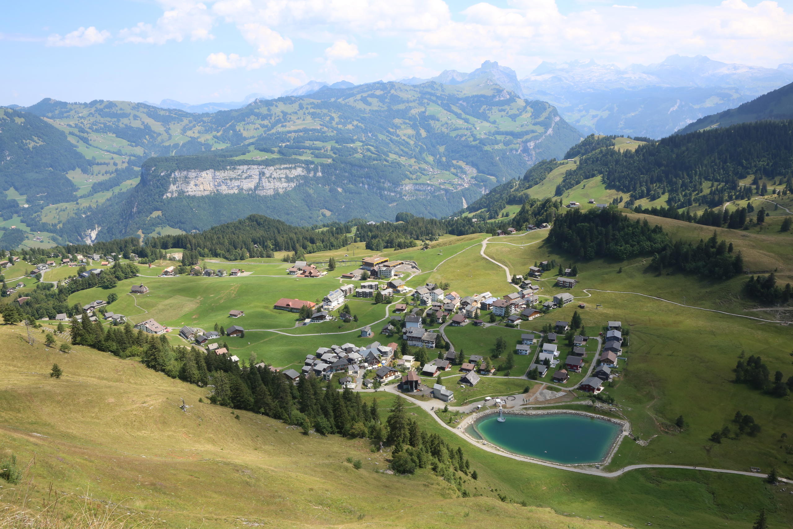 Das Bergdorf Stoos und sein kleiner Stausee aus der Vogelperspektive