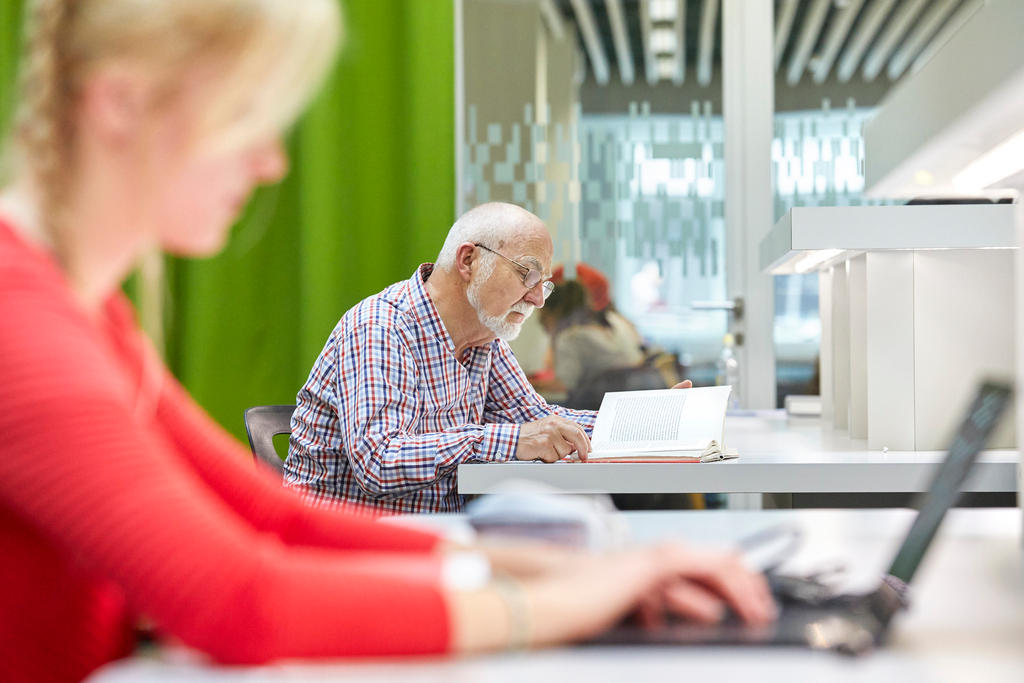 A young woman works next to an older man