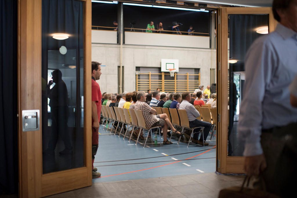 Rows of people sitting in a gym hall.