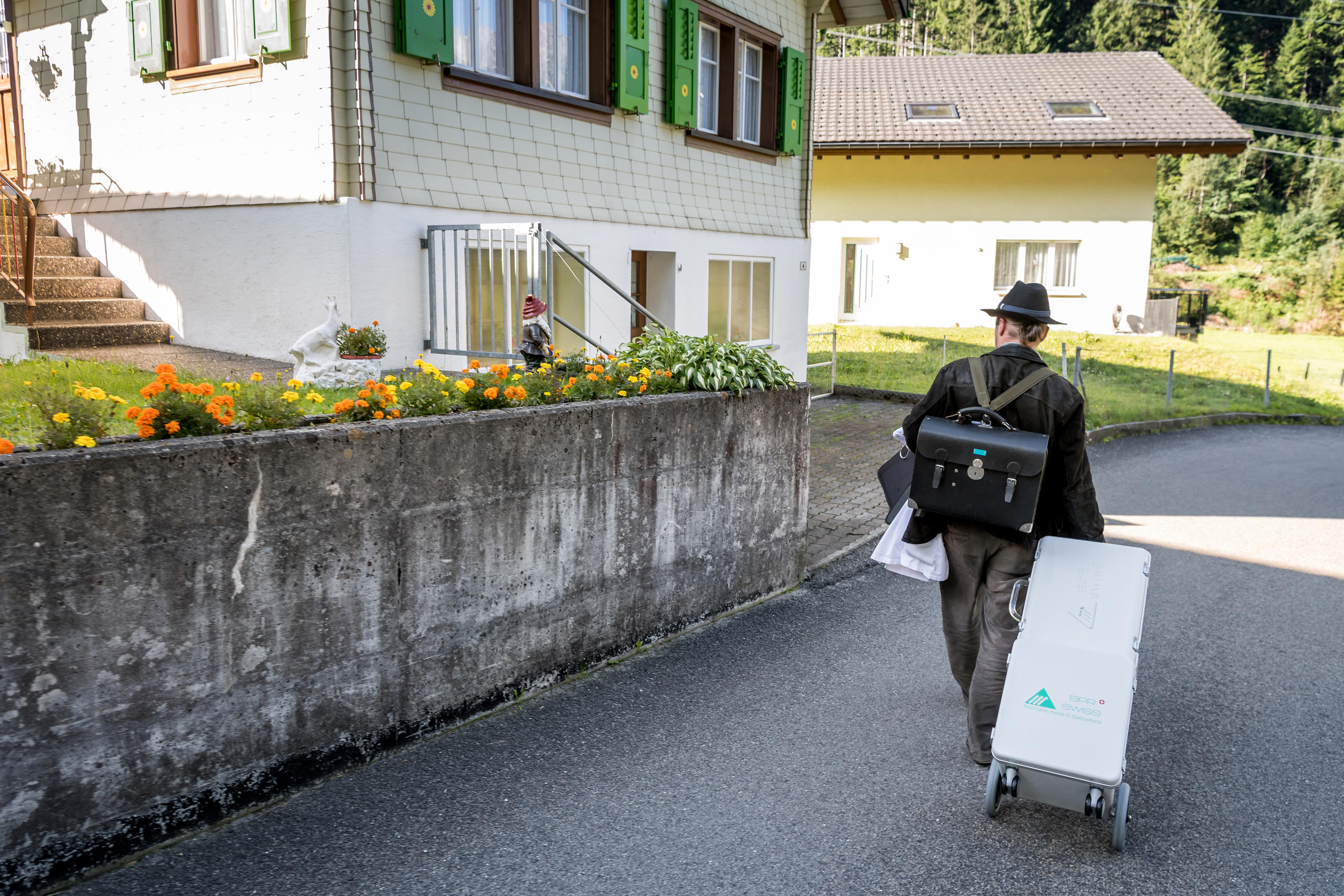 Rückenansicht des Zahnarztes mit Rollkoffer