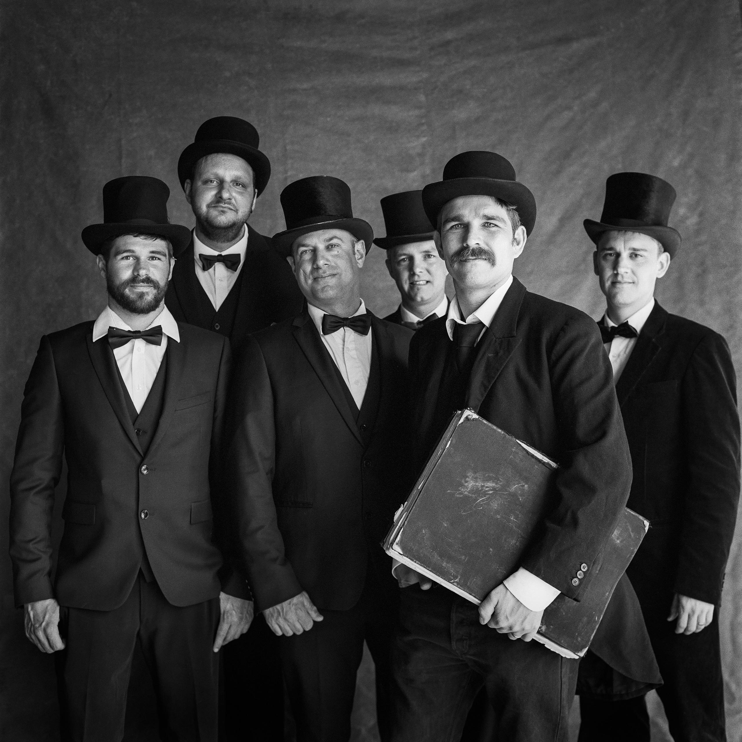 Grupo de hombres vestidos de jueces con bombín y corbata de moño.