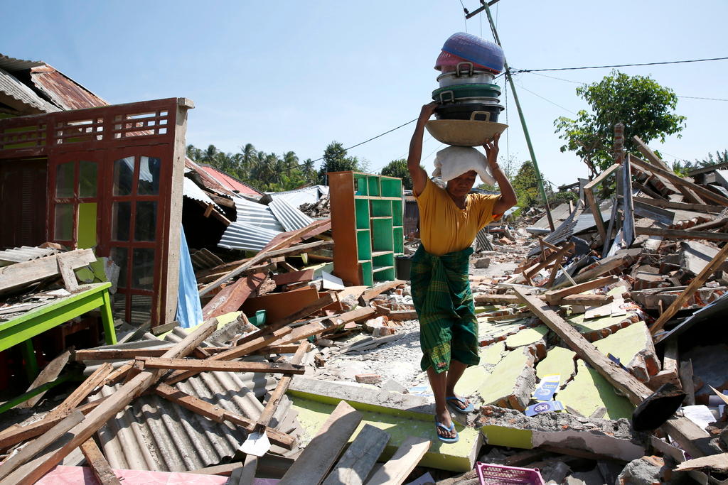 Woman carrying belongings amidst rubble