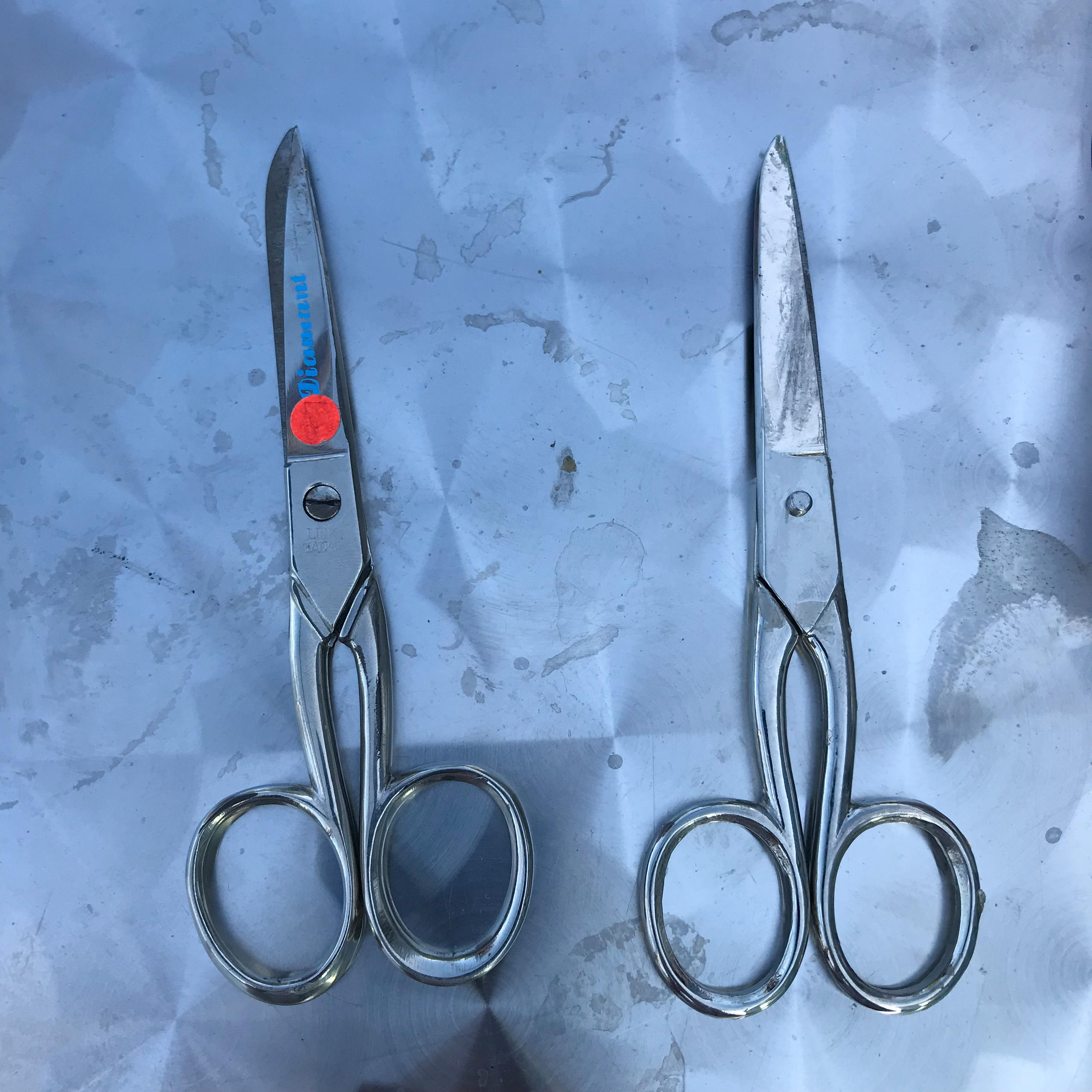 Two pairs of scissors, one marked with red tape