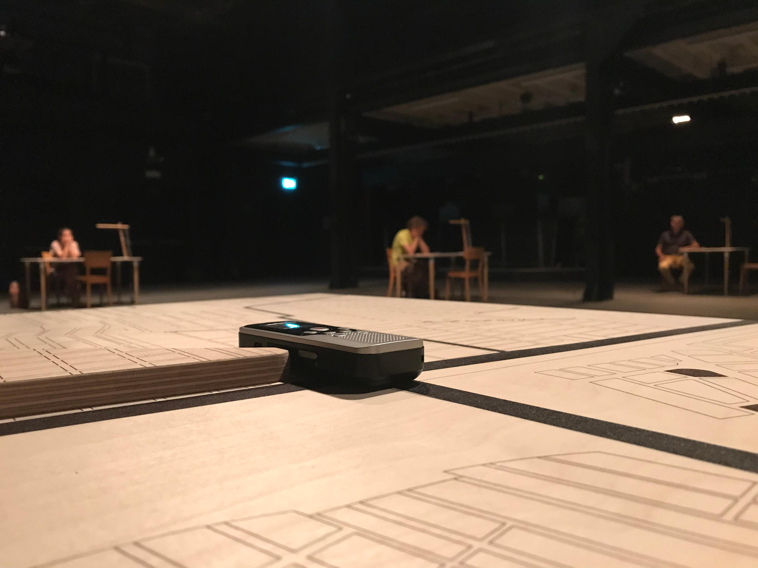 سطح طاولة خشبية وعليها آلة تسجيل داخل قاعة عروض مسرحية مظلمة