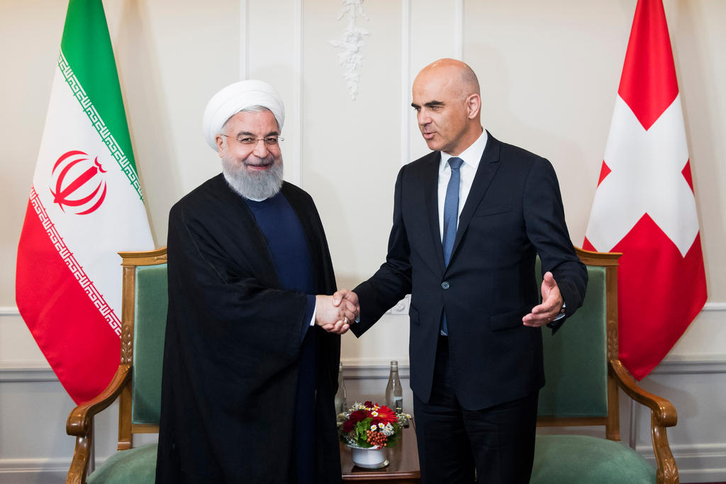 مصافحة بين رئيسي سويسرا وإيران وفي الخلفية علما البلدين