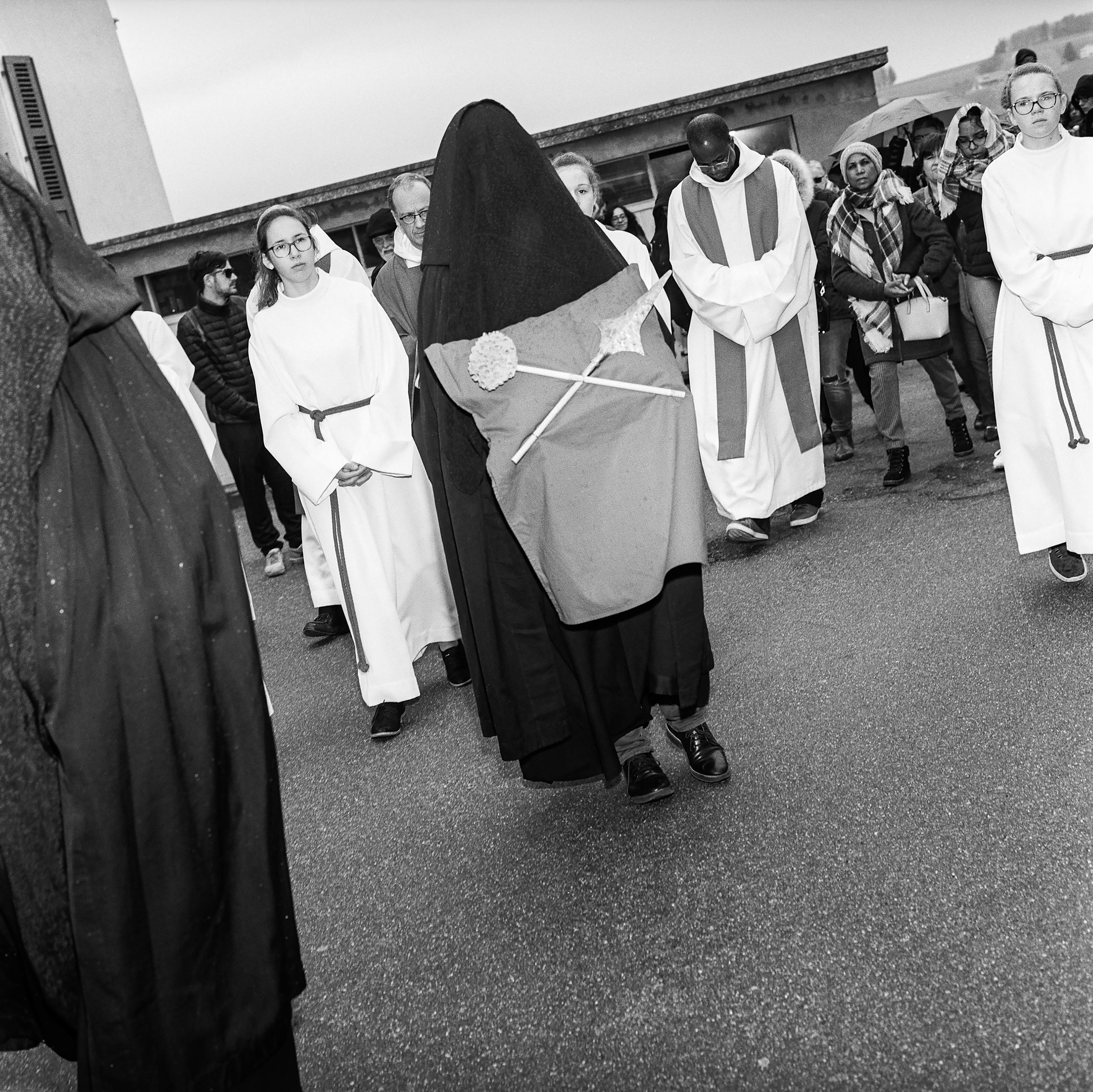 Frau in Schwarz trägt Lanze und Schwamm, dahinter laufen Kirchenleute in Weiss