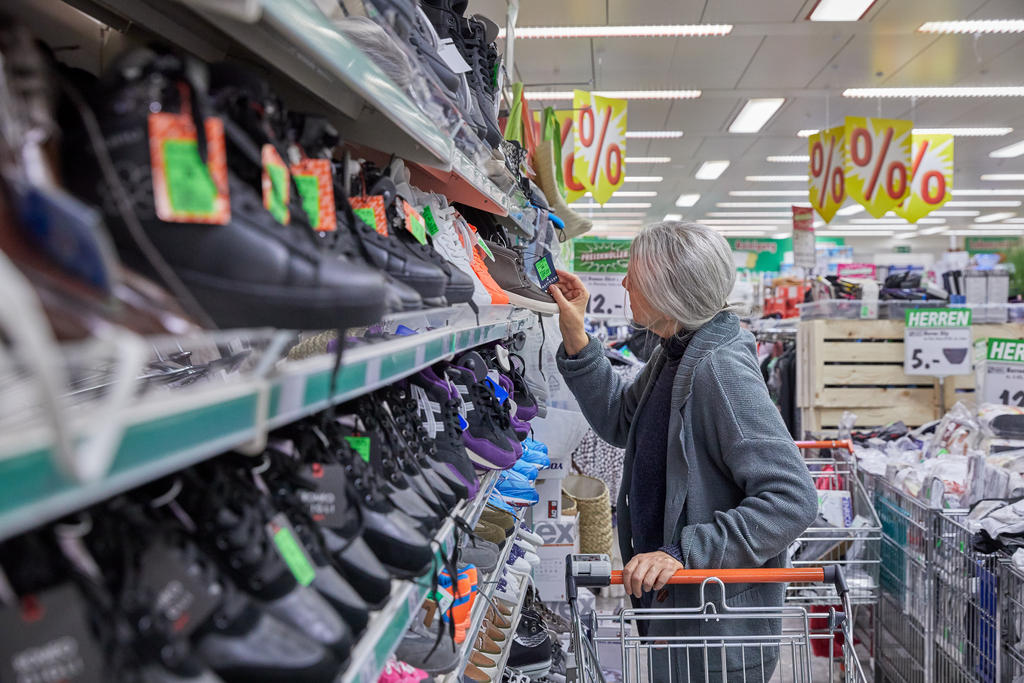 Une femme dans un supermarché regarde les chaussures à prix réduit