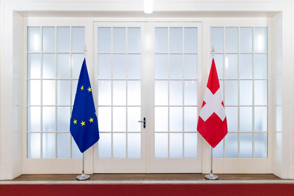 EU- und Schweizer Flagge in einem Raum vor einem Fenster