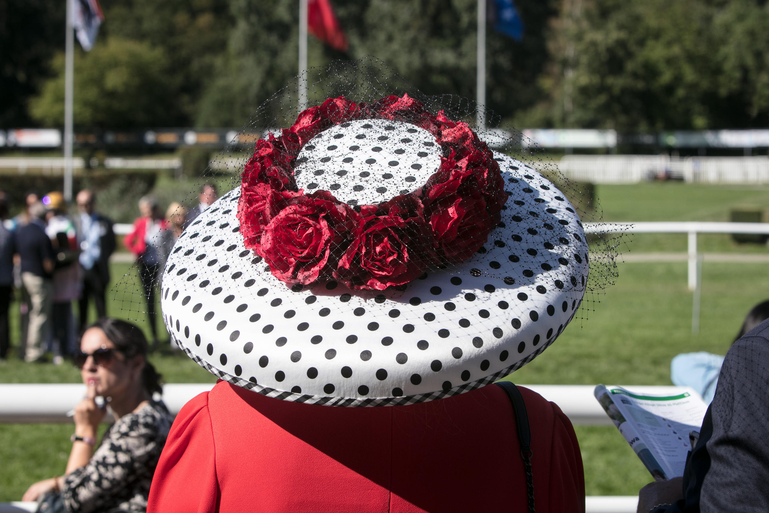 primo piano su un cappello bianco a pois neri e con una corona di rose rosse