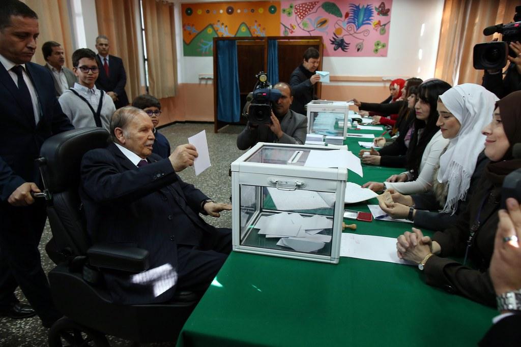 رجل على كرسي متحرك يضع بطاقة اقتراع في صندوق بلوري