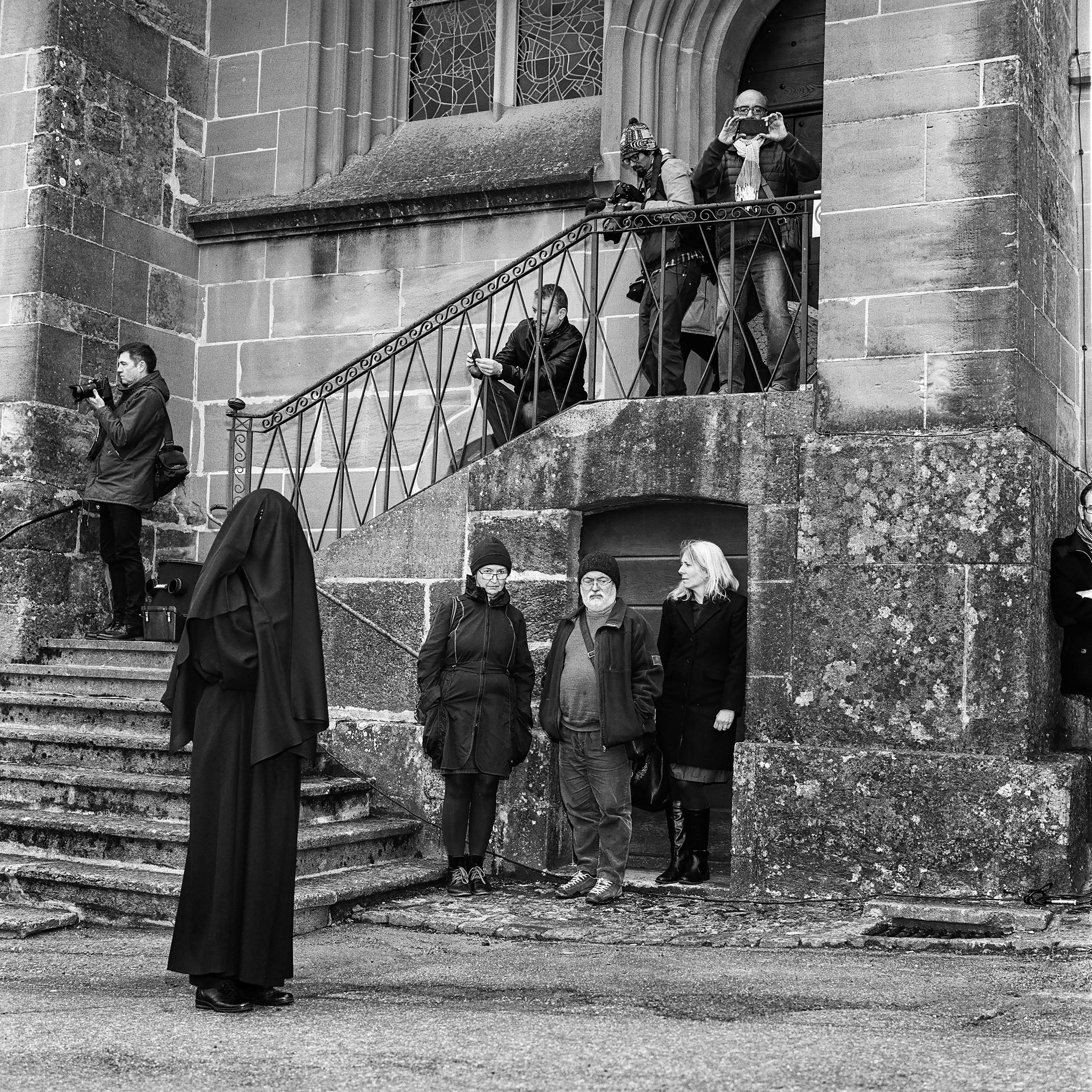 Frau in Schwarz und Fotografen vor der Kirche