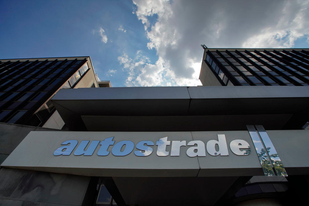 Vista dal basso dell entrata di un edificio a vetri, con insegna Autostrade in primo piano e nuvole sopra