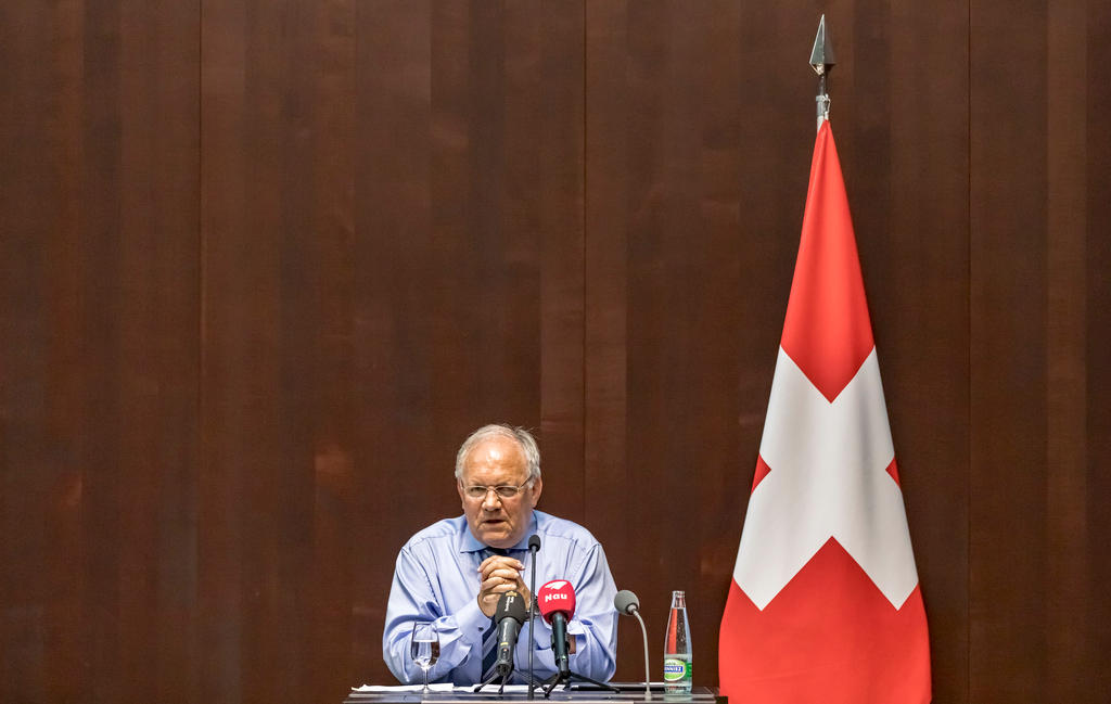 Schneider-Ammann durante la conferenza stampa accanto a una bandiera svizzhera