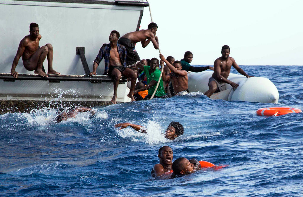 Un operazione di salvataggio di migranti scappatati dalla Libia: si vedono diverse persone cadute in mare