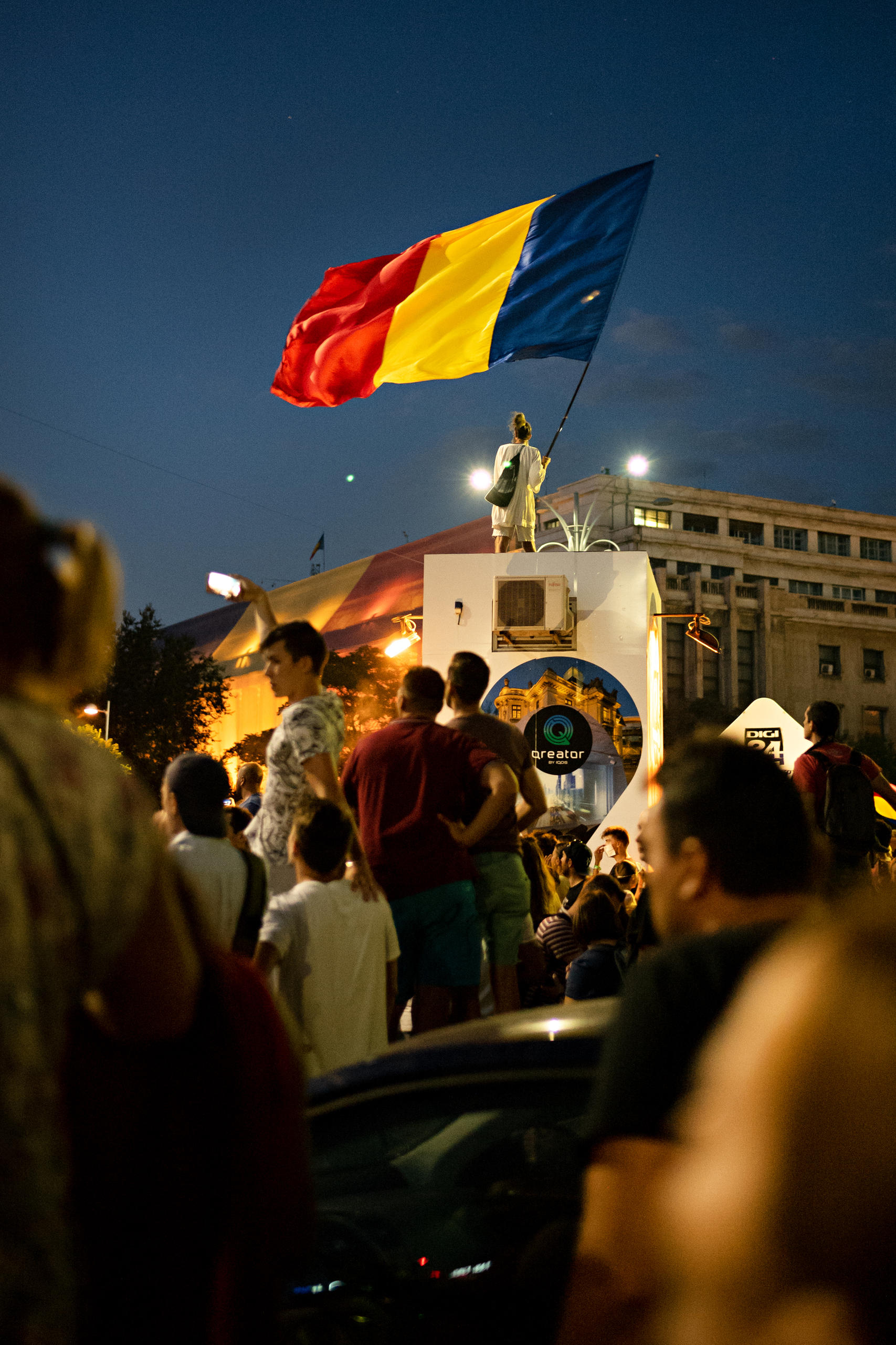 Frau mit grosser rumänischer Flagge auf einem hohen Sockel in Bukarest