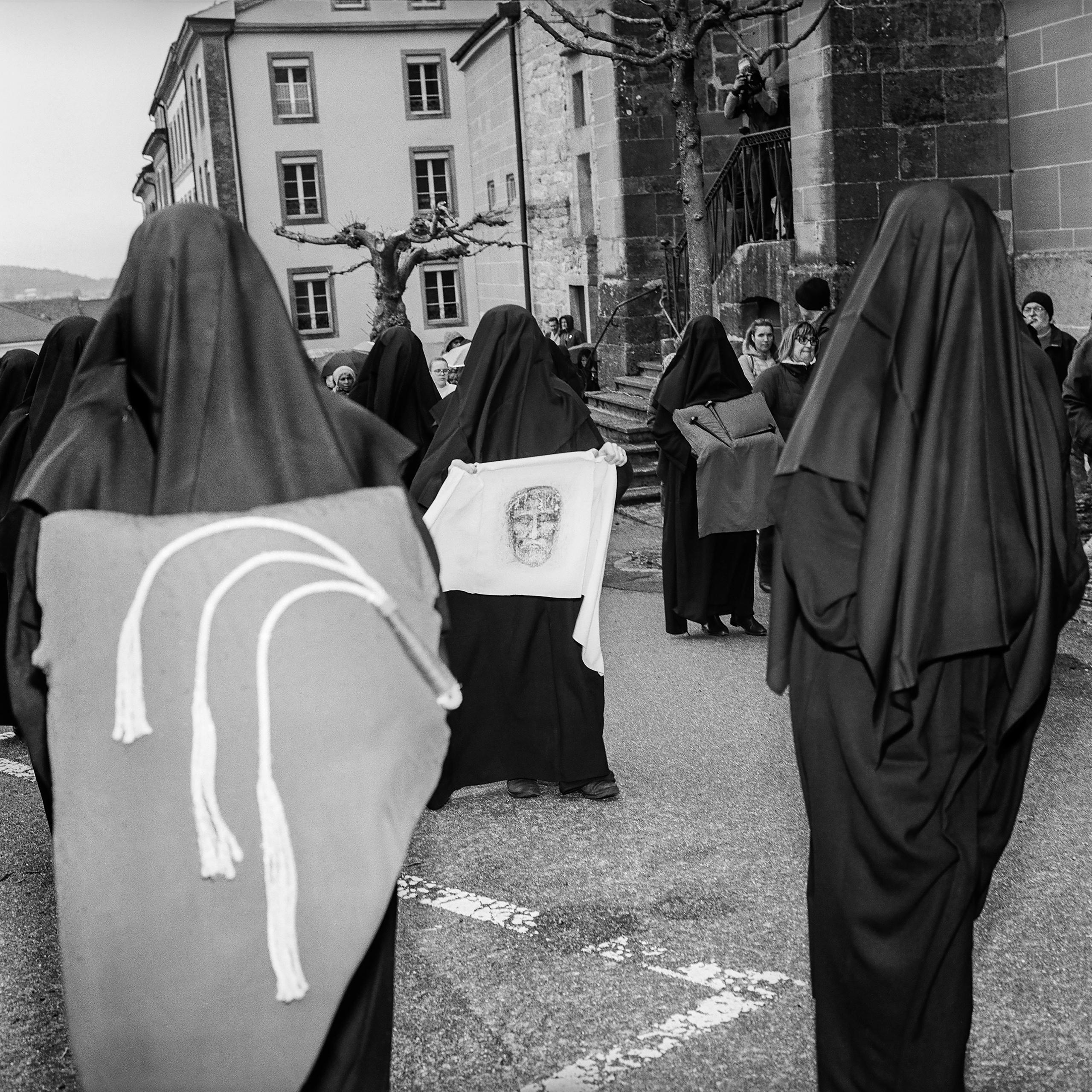 Frauen in Schwarz tragen eine Peitsche, ein Tuch mit Christuskopf und Nägel