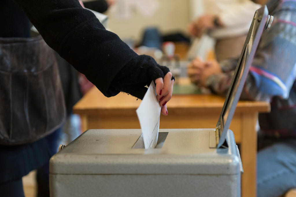 A person puts their voting paper in the ballot box