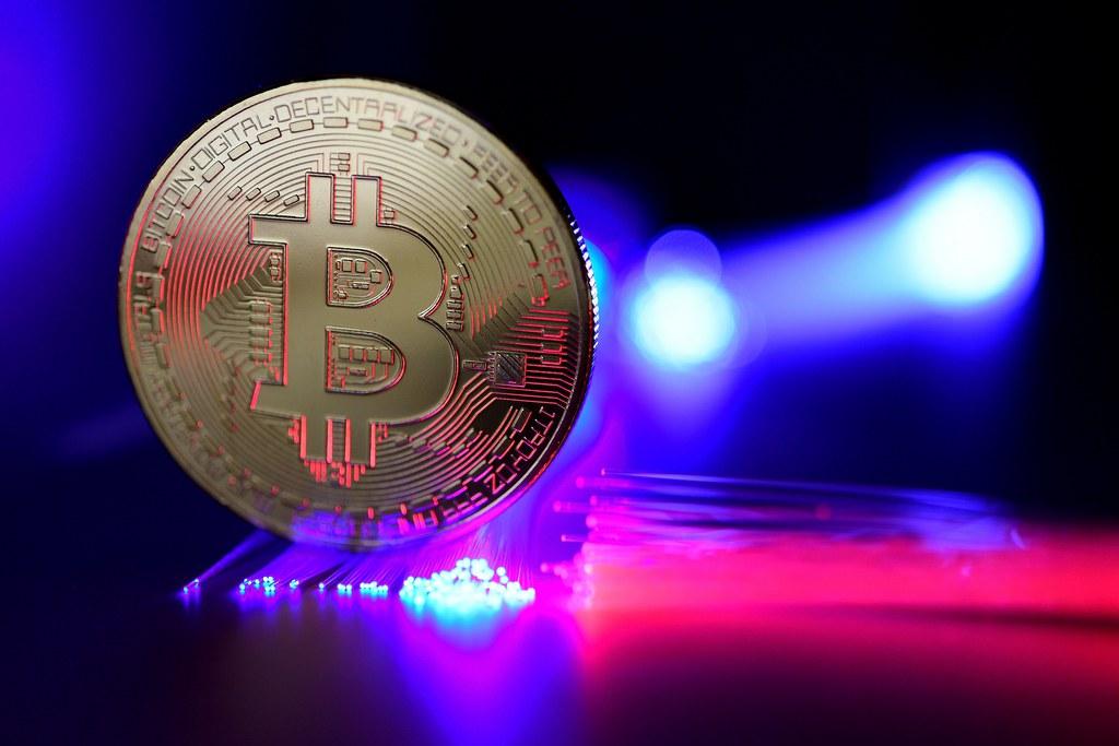 A bitcoin lit up by colourful laser lights