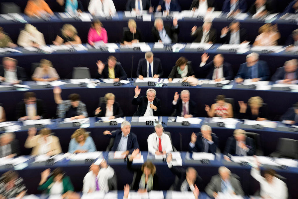 رجال ونساء جالسون فوق مقاعد في مقر البرلمان الأوروبي