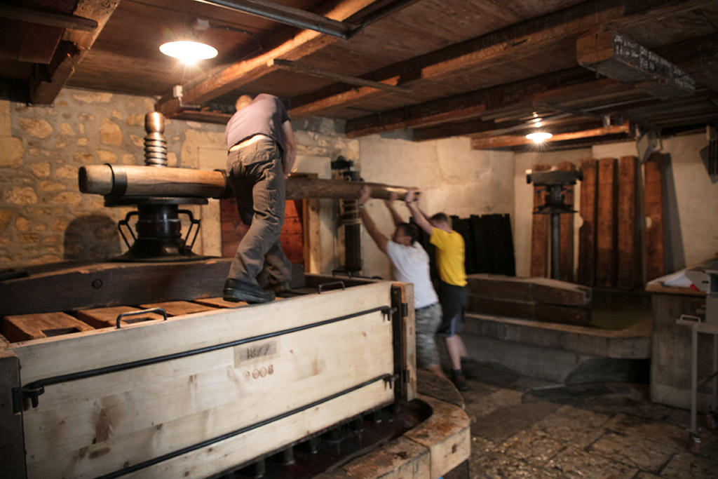 Men turn a torque of a wine press