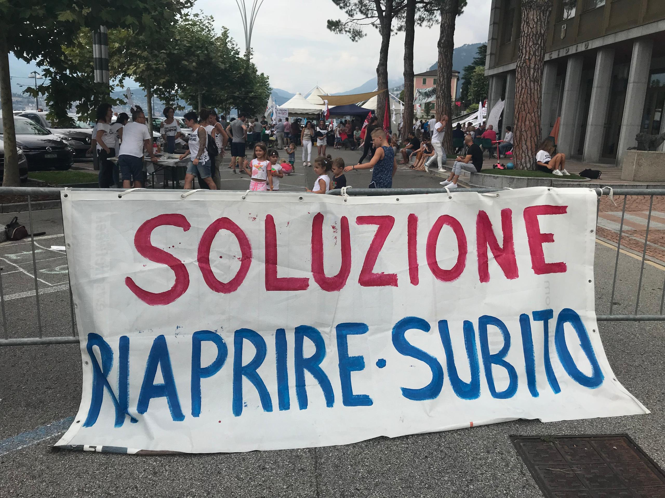 Un cartello a Campione con scritto. Soluzione, riaprire subito