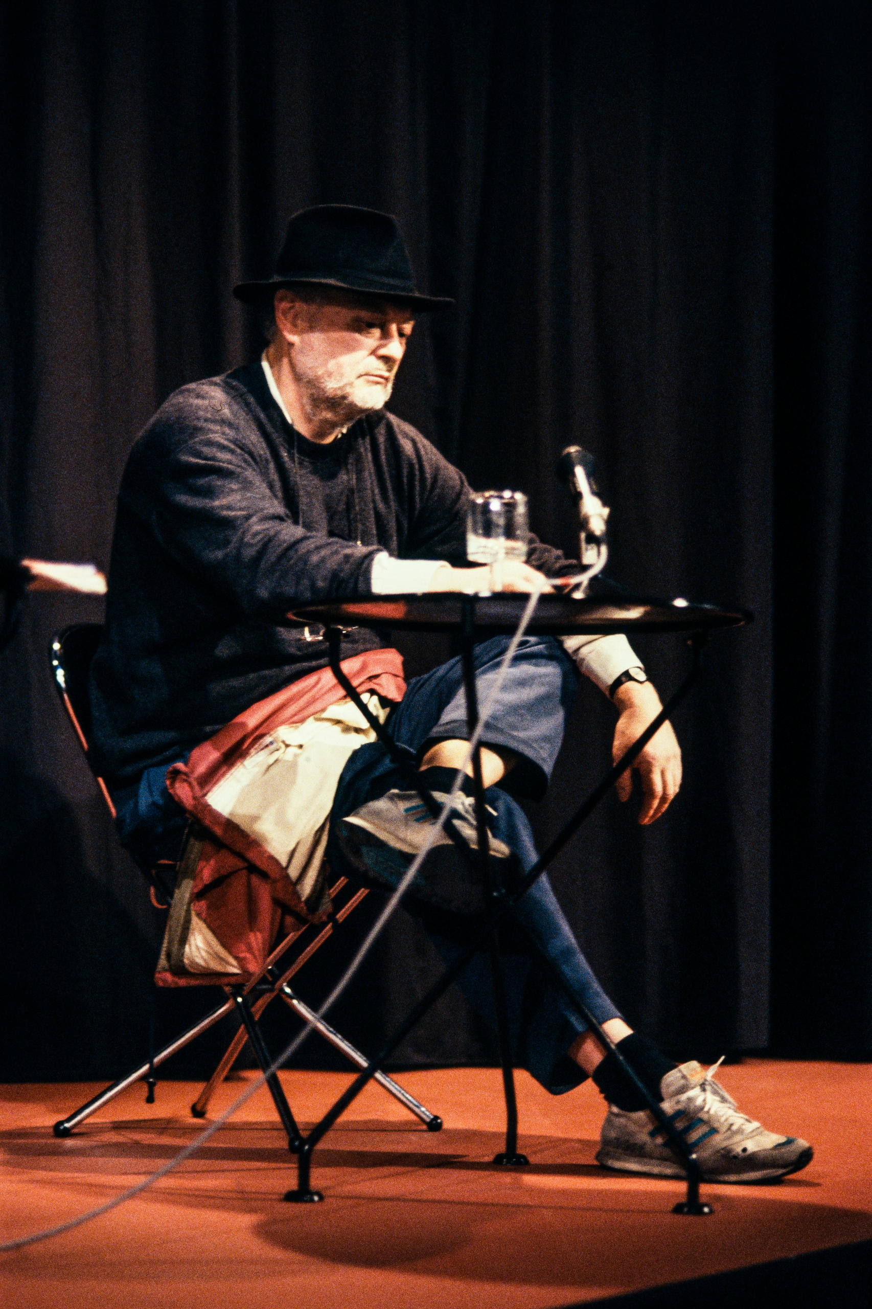Farbfoto: Meienberg auf einer Bühne am Vorlesen