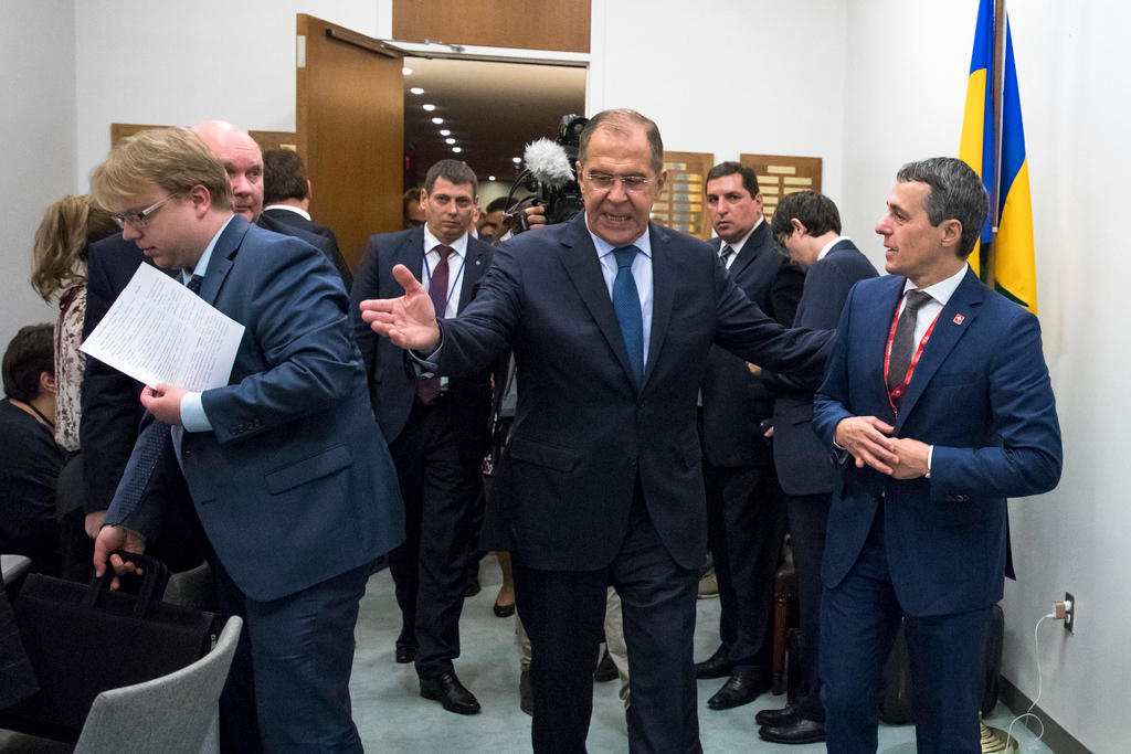 Sergej Lavrov prende per il braccio Ignazio Cassis e gli indica il passo; tutt attorno funzionari e assistenti
