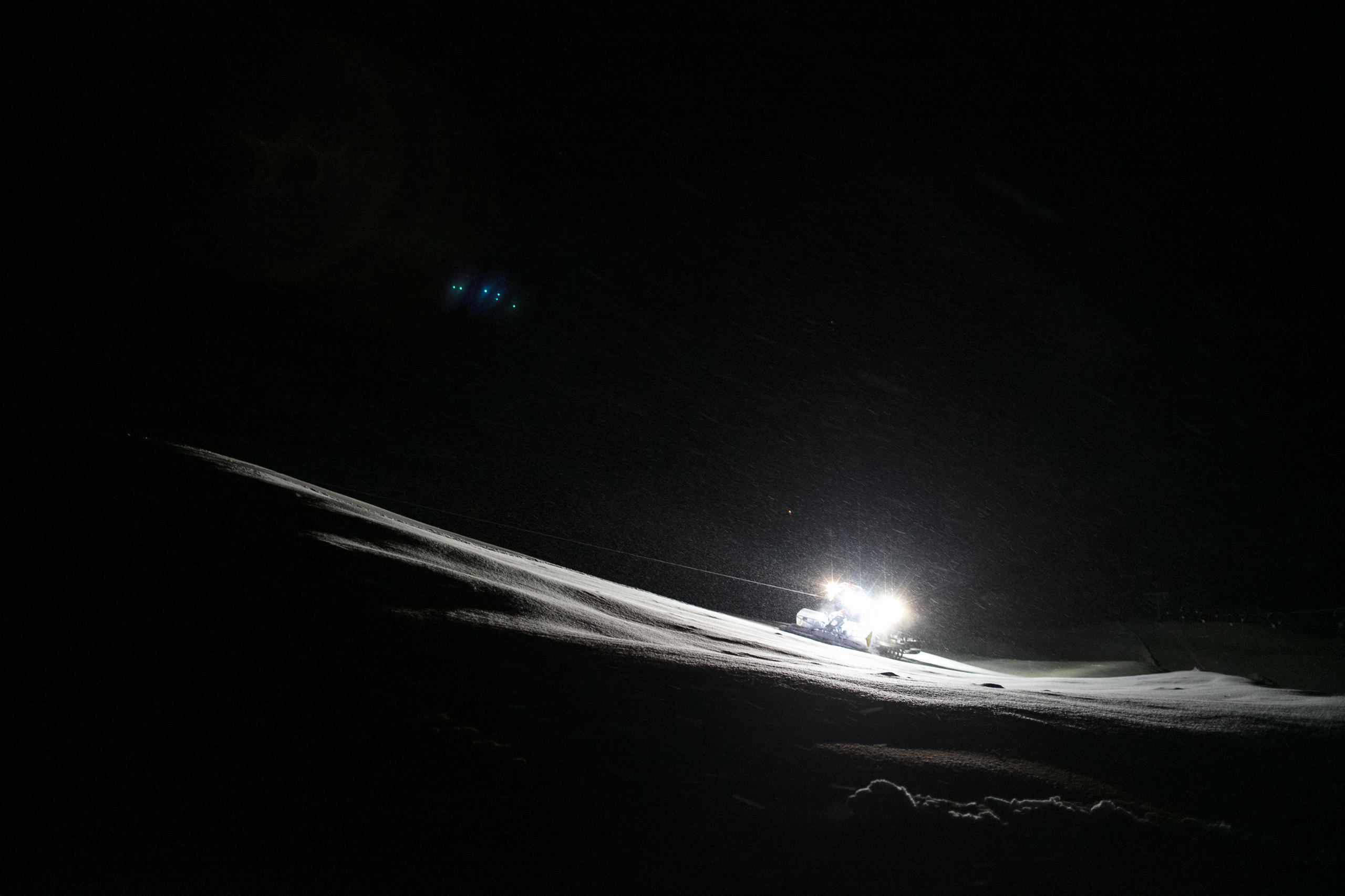 Une dameuse dans la neige dans la nuit