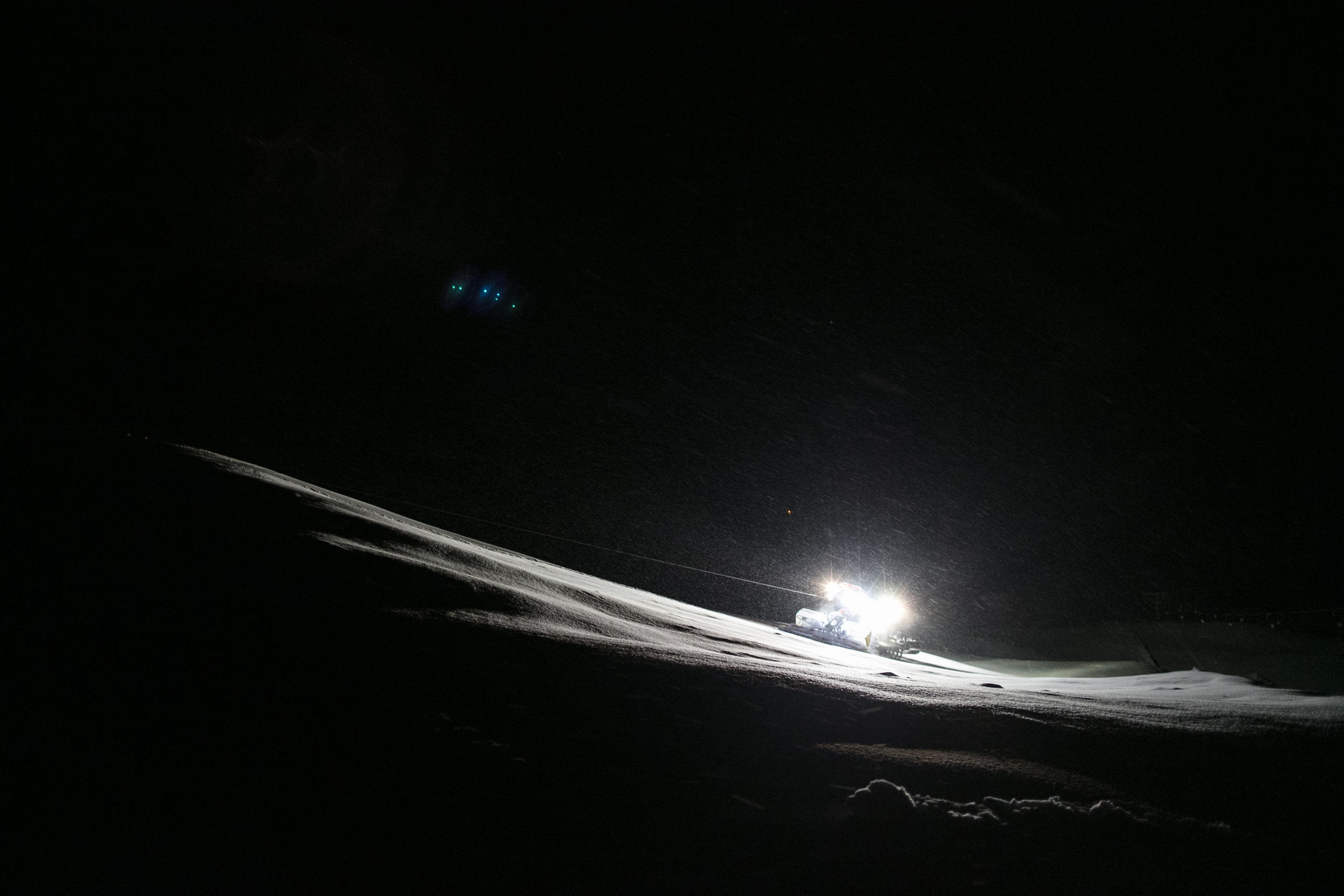 Piste basher lit up at night