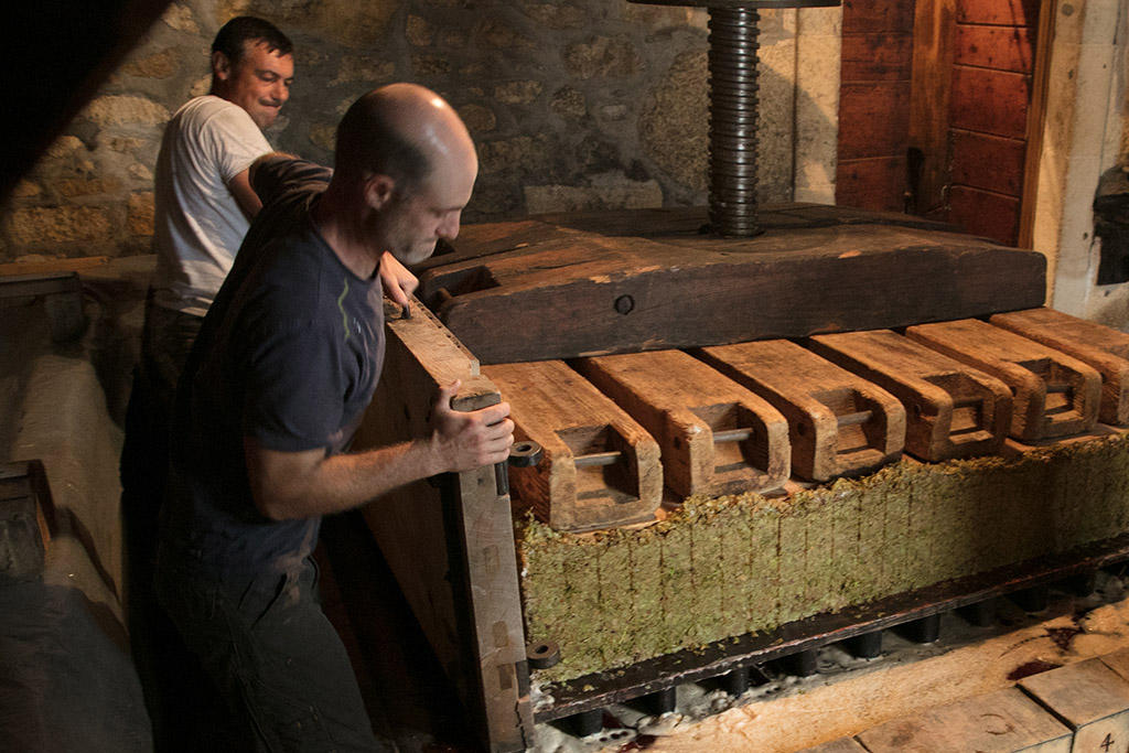 Zwei Männer tragen die Holzwand einer Weinpresse