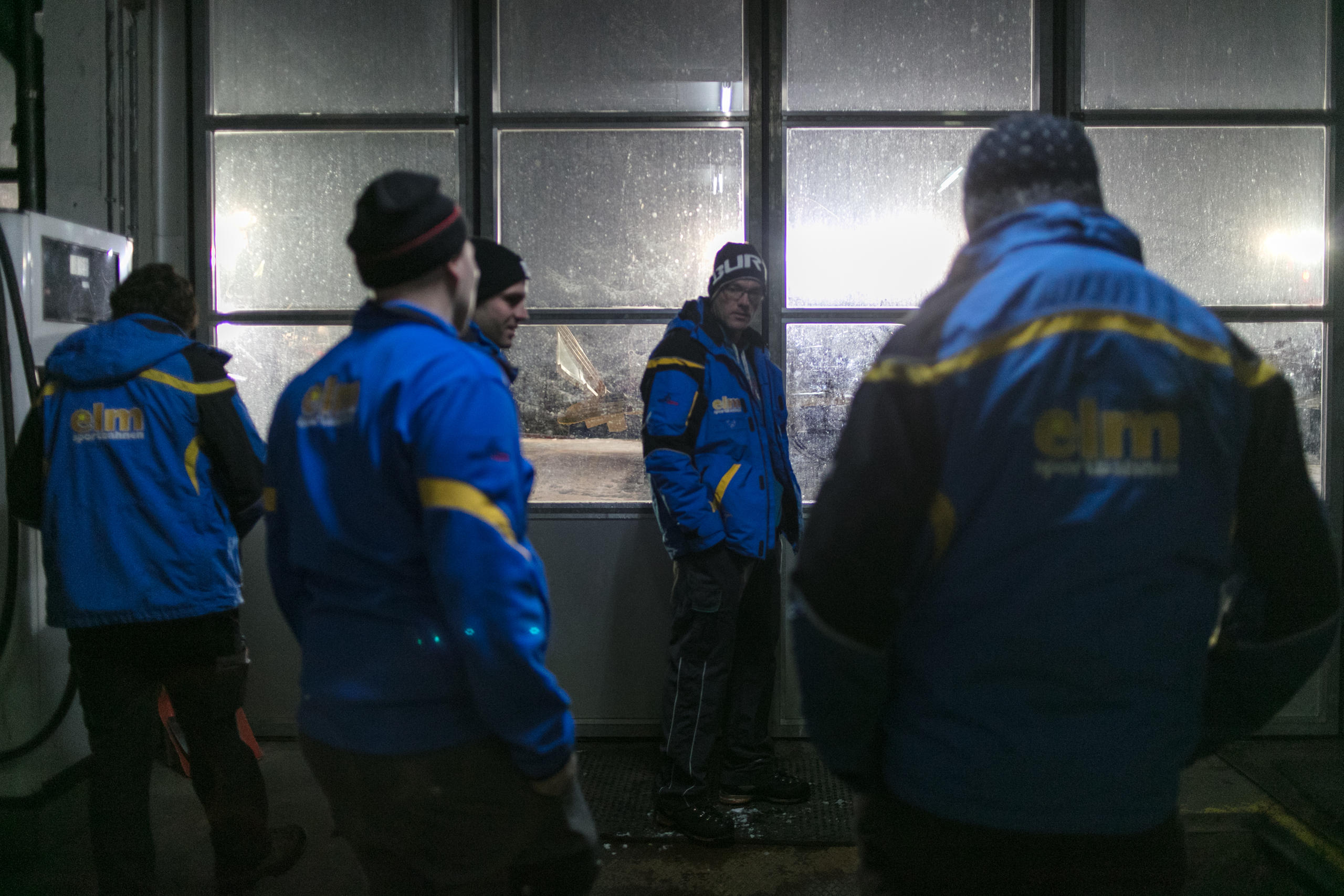 Fünf Männer in dicker Winterbekleidung stehen in der Garage