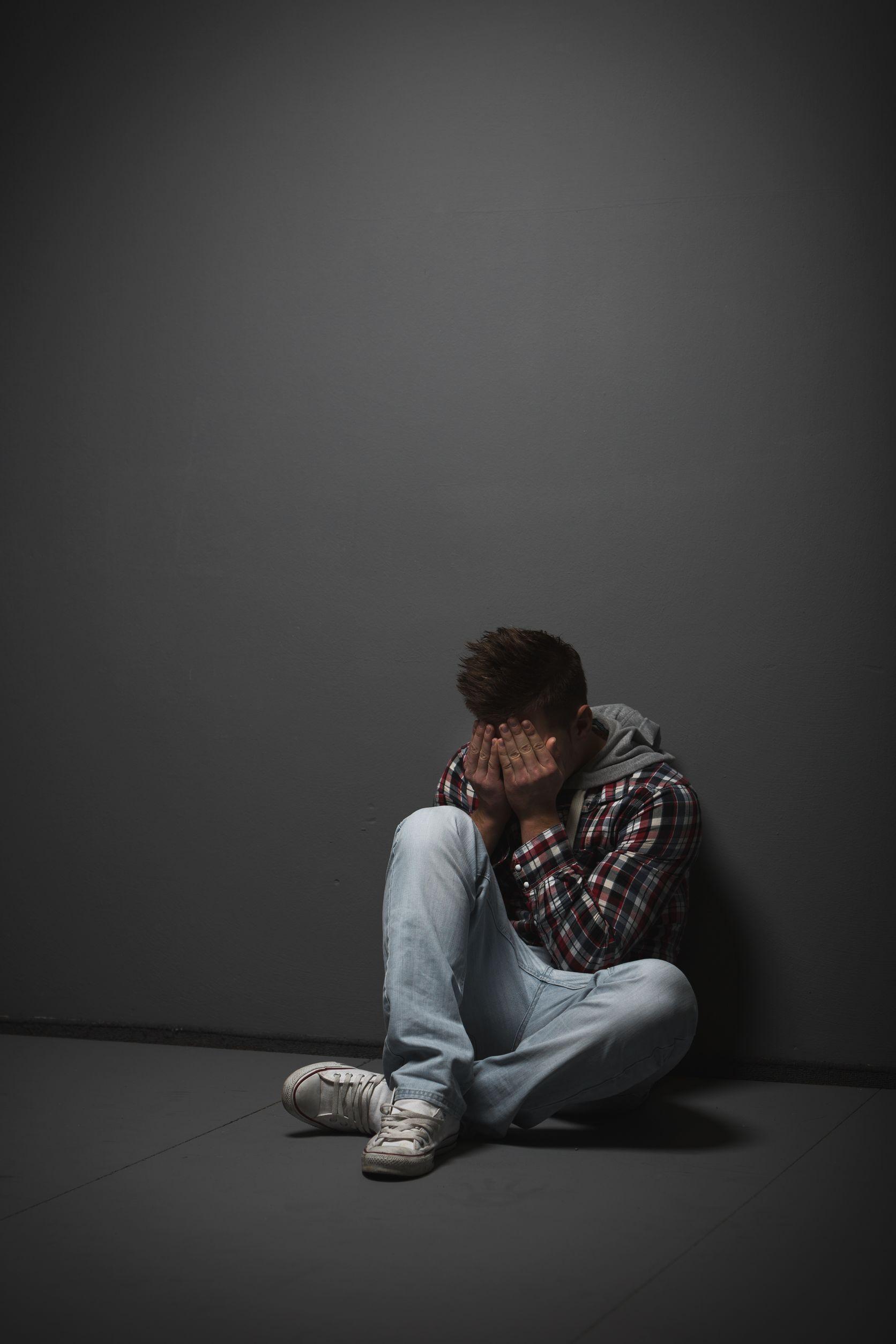 A young man covering his face with hands