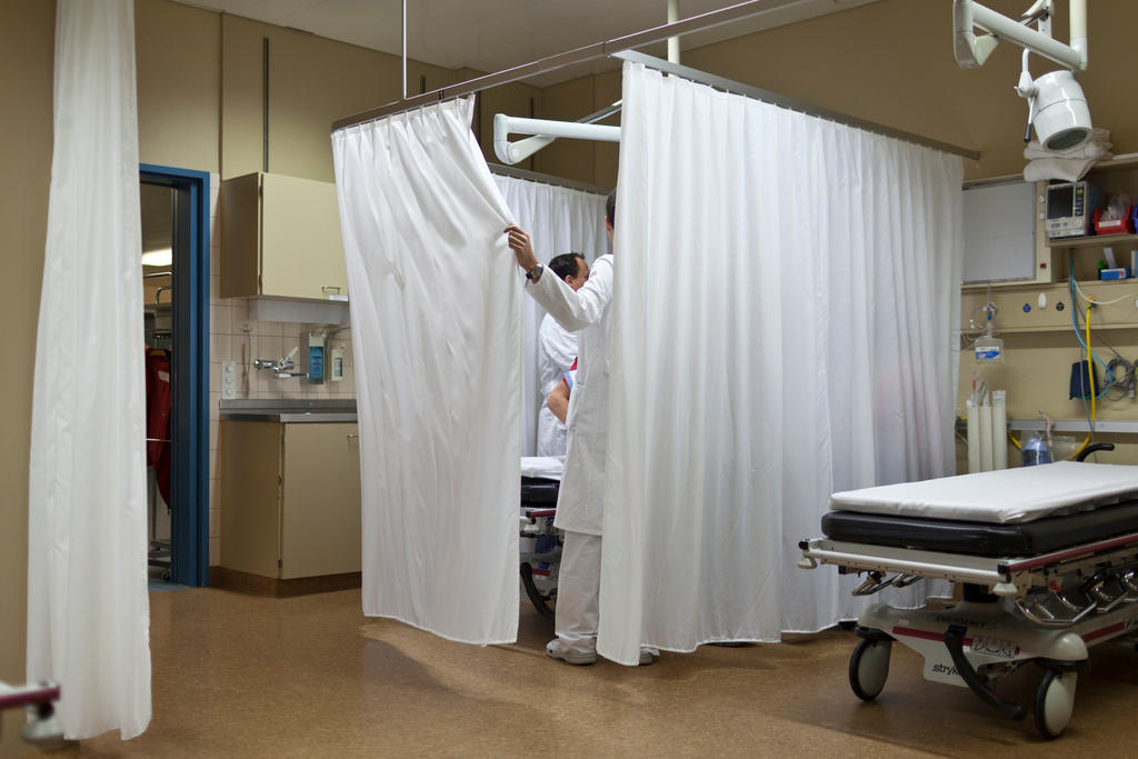 A doctor draws the curtain on a patient bed in an emergency room in Graubünden