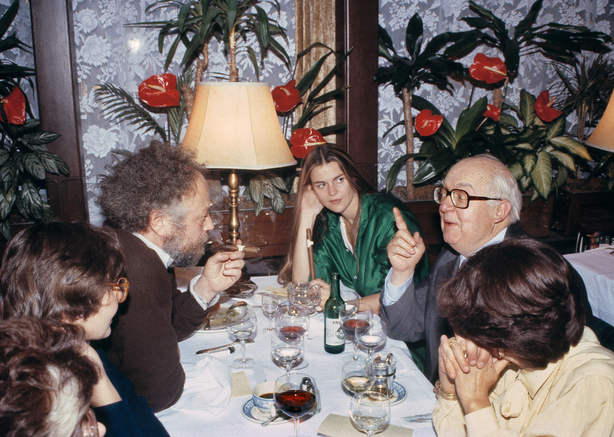 Farbfoto: Sechs Personen unterhalten sich am weiss gedeckten Tisch.