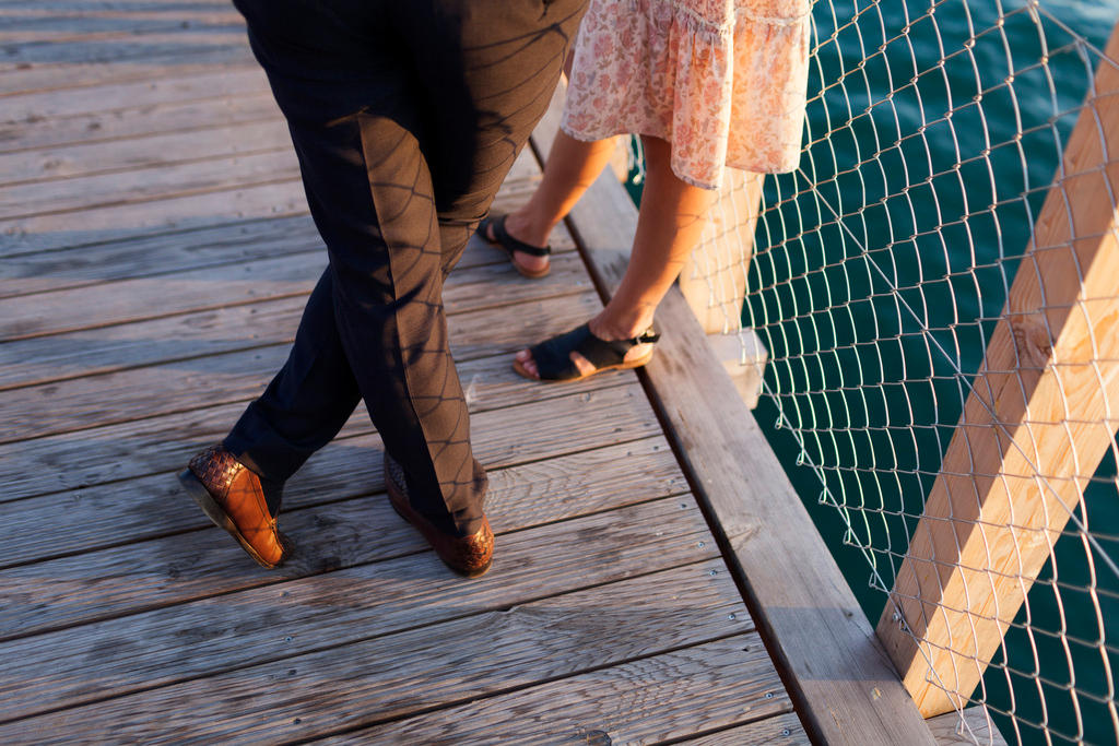 A man, in dress pants and leather loafers, and a woman, in a summer skirt and sandals