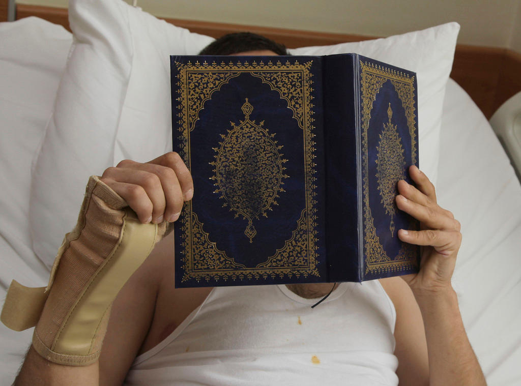 man in hospital bed reads Quran