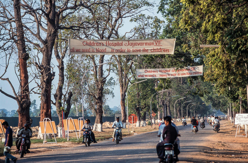 Street scene with cyclists and banners above the road.