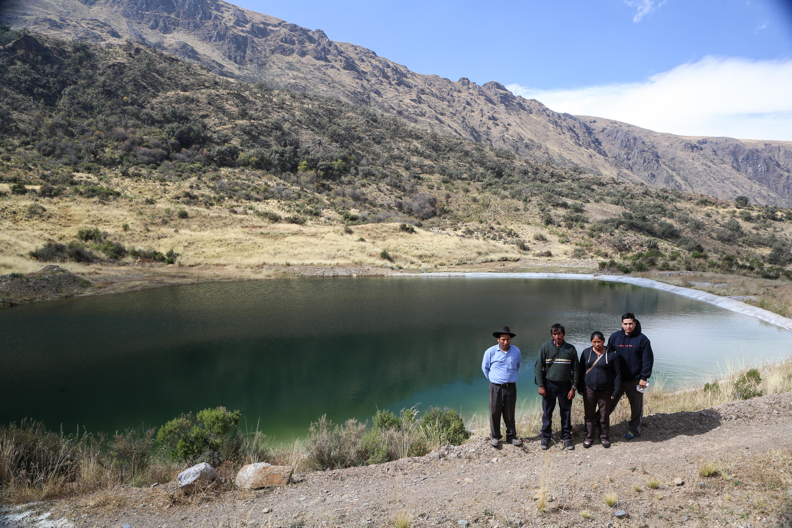 Vier Personen vor einem kleinen Stausee in den Anden