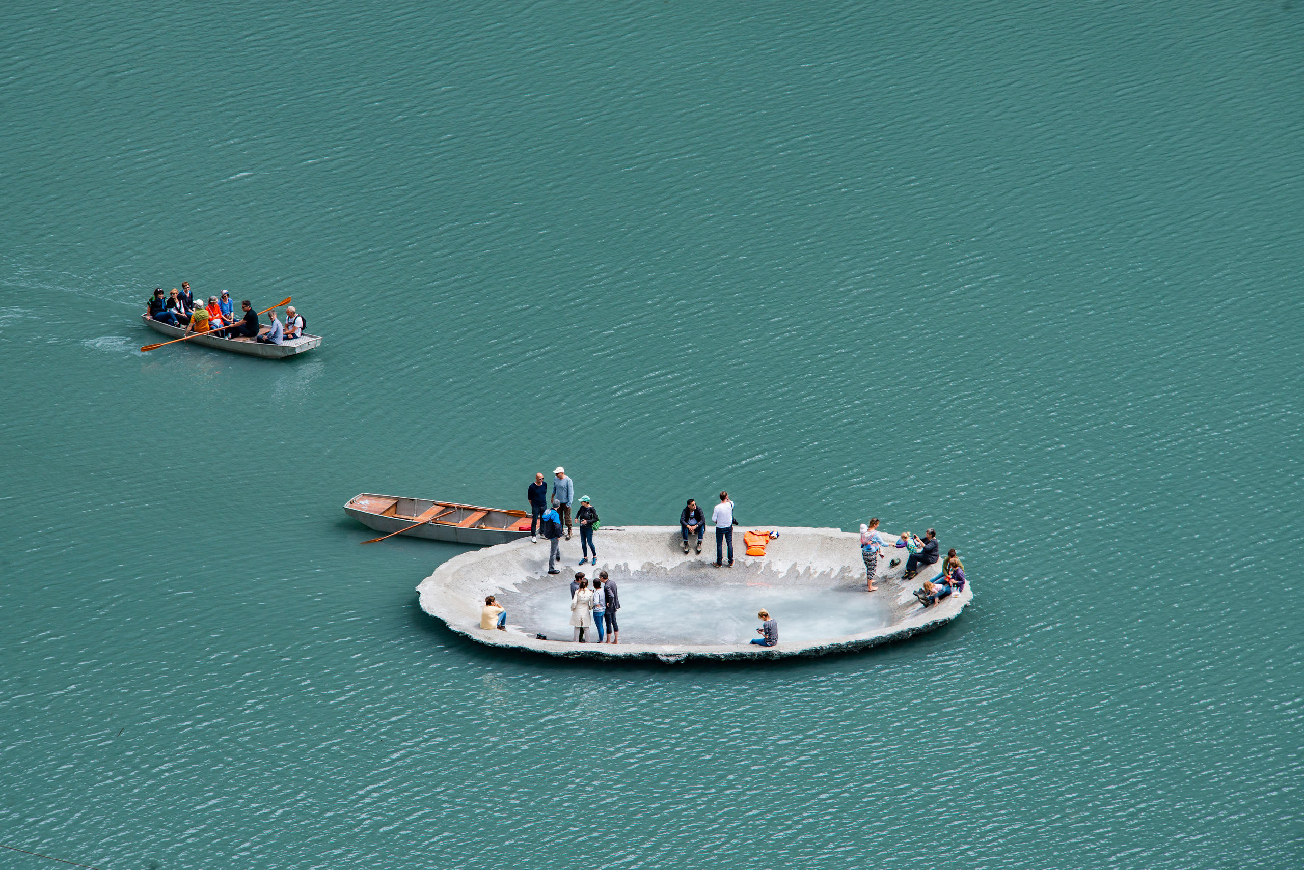 People sitting in a concrete shell in the middle of a lake.