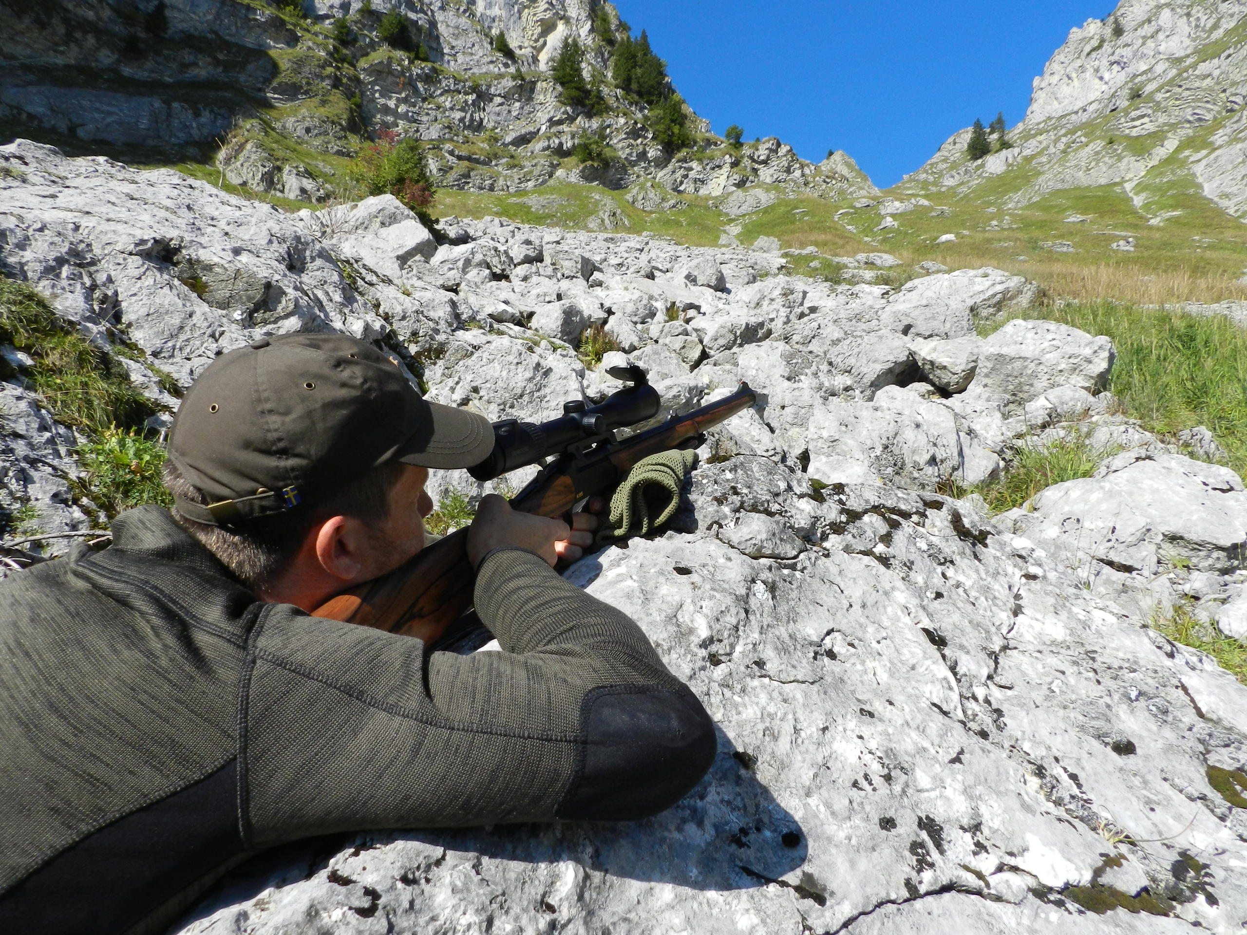 Hunter takes aim with his rifle in the mountains