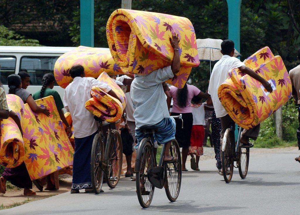 People riding bicycles while carrying mattresses
