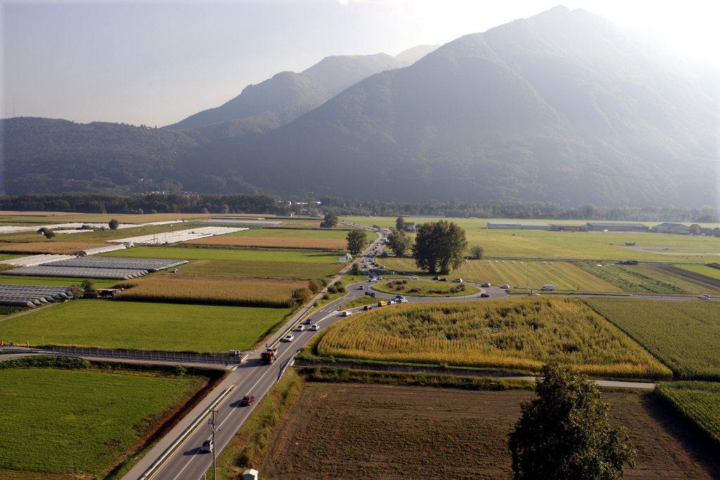 strada in mezzo a prati e campi e sullo sfondo le montagne.