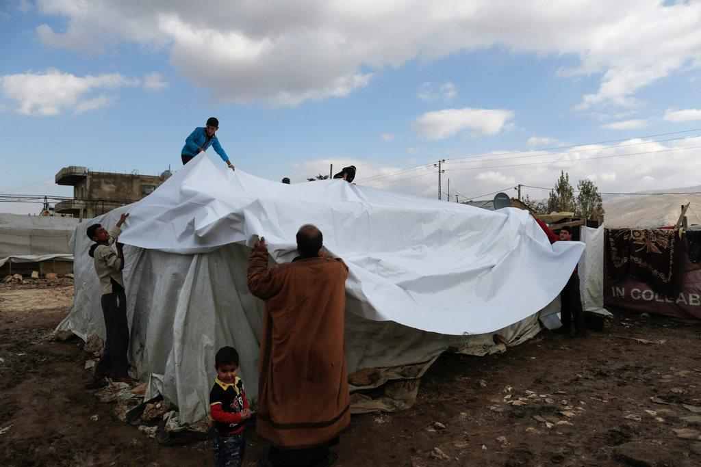 Young and older people building a tent.