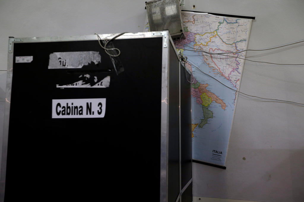 A voting booth and a map of Italy on the wall
