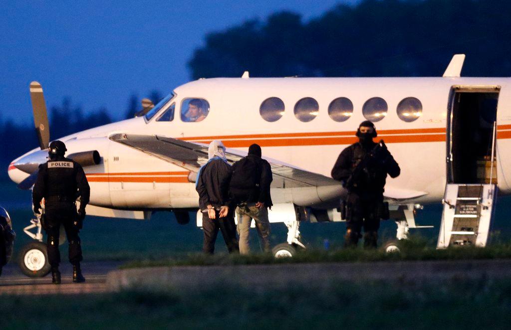 An alleged Jihadist (2-L) is escorted by French police onto an airplane