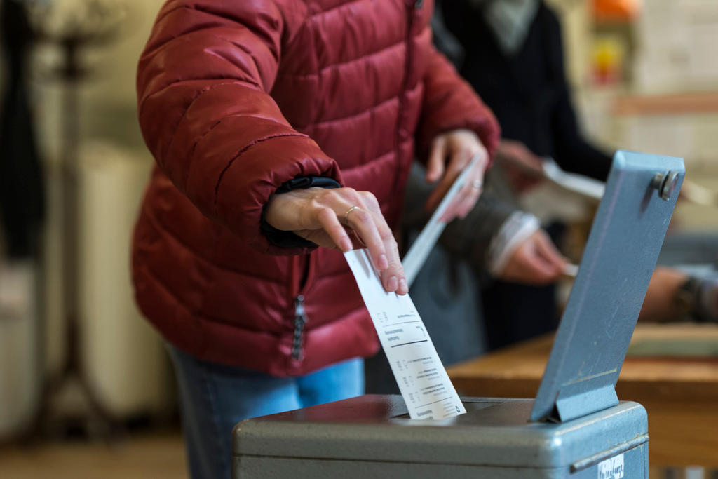 una donna infila una scheda in un urna