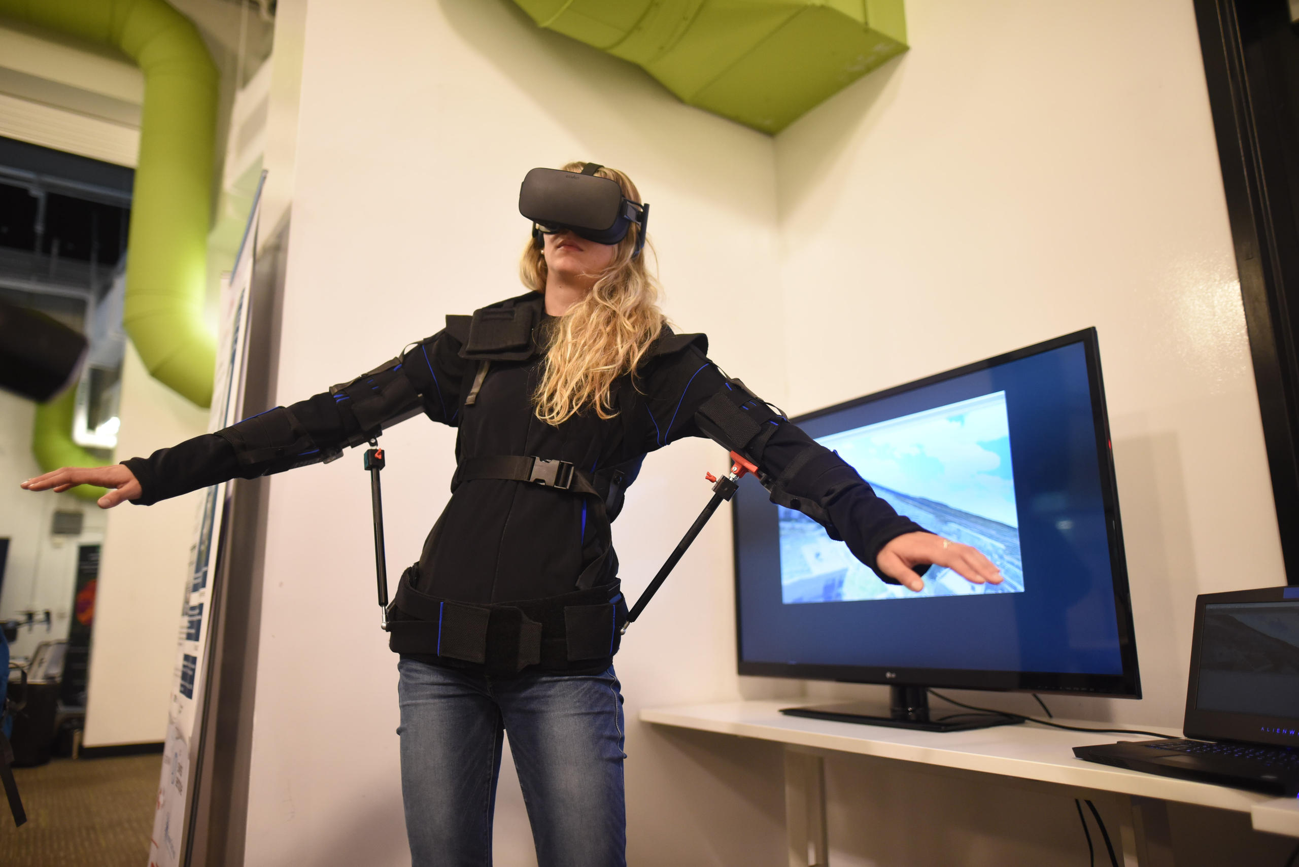 A woman demonstrates EPFL s FlyJacket, which allows users to pilot drones within an immersive VR environment.