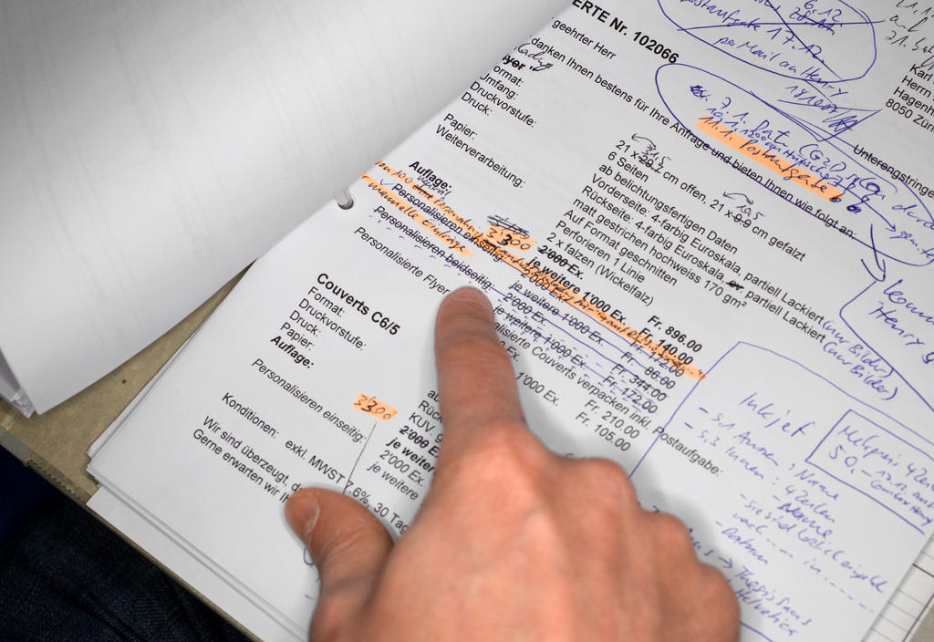 A finger points to a line on a budget sheet