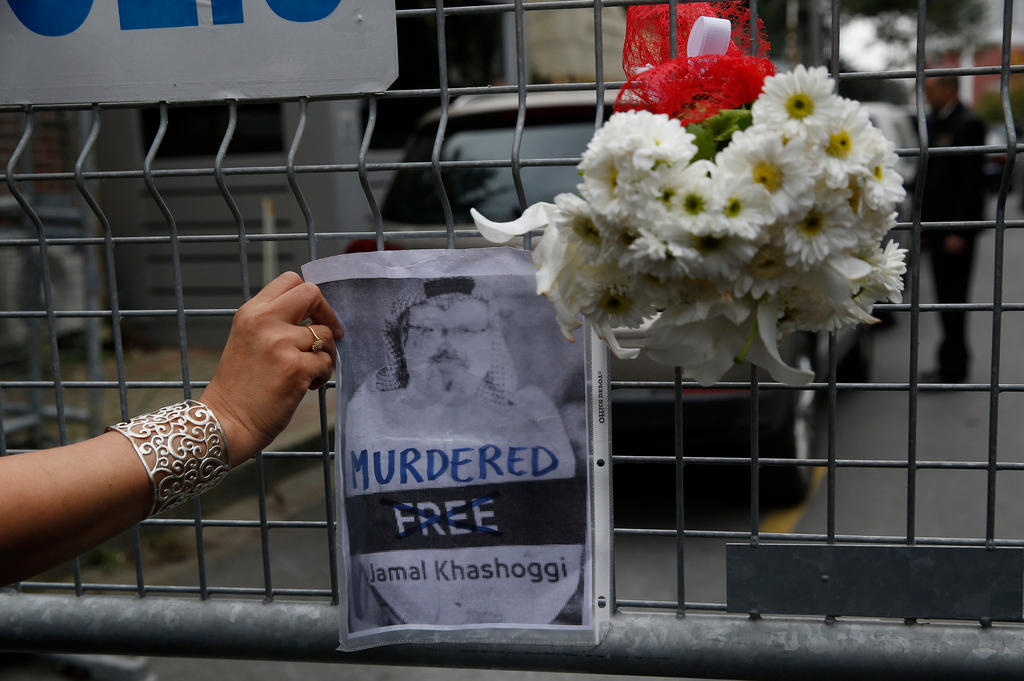 Woman attaches a picture of Jamal Khashoggi on a barrier in Istanbul